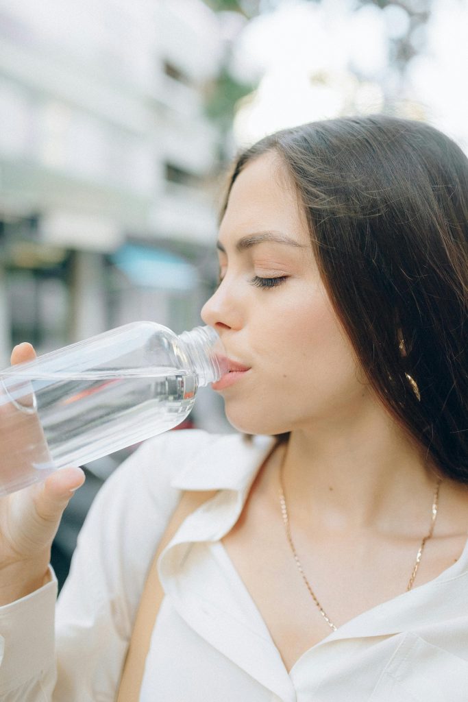 Woman in Button Down Shirt Drinking a Bottled Water